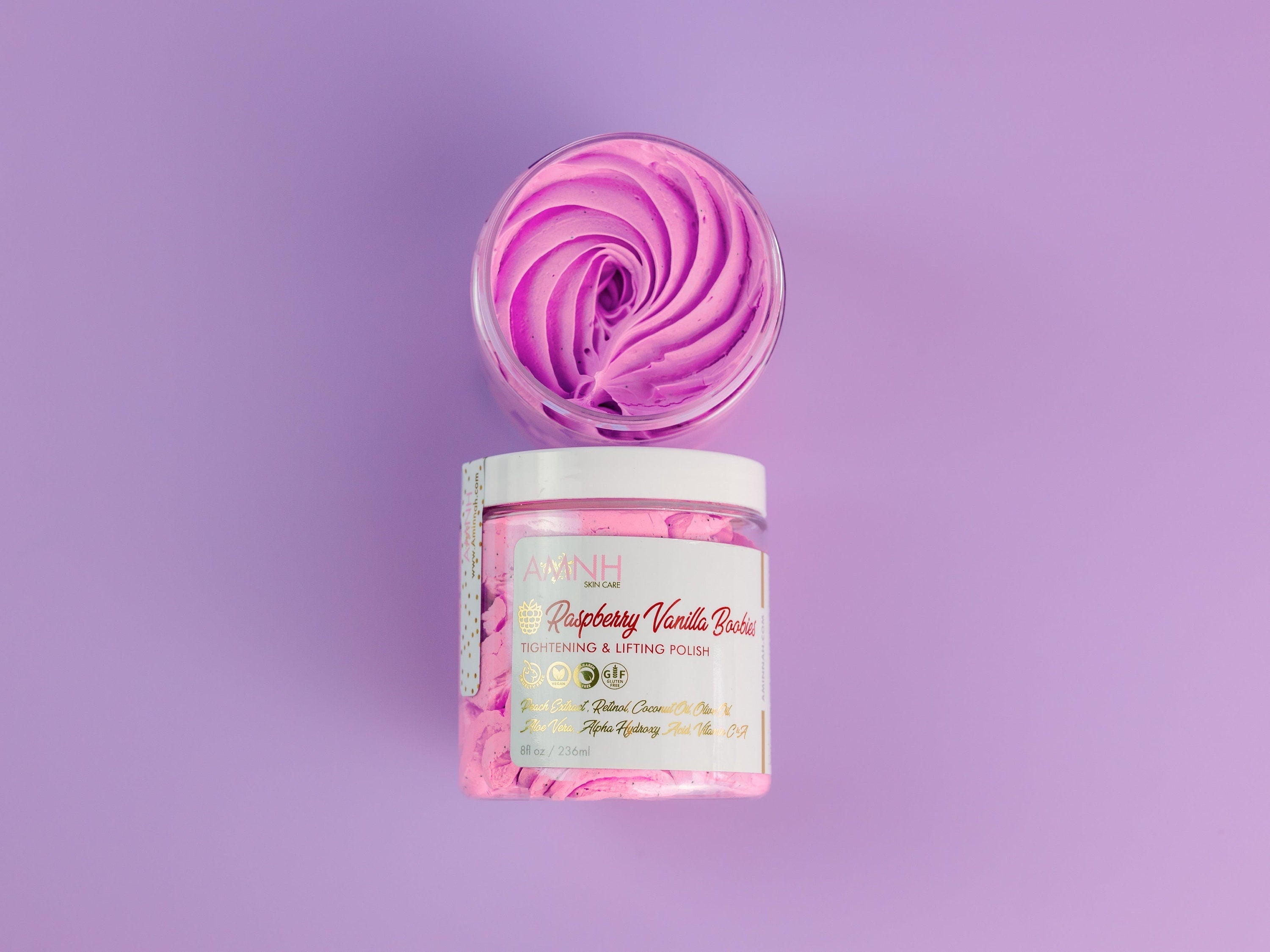 Raspberry Vanilla Boobies Tightening & Lifting Sugar Scrub with whipped raspberry-pink exfoliating polish in a reusable jar, luxury body exfoliant made with natural ingredients to gently smooth, soften and renew skin. Clean beauty, vegan, cruelty-free, paraben-free, gluten-free formula in recyclable packaging from a female-owned brand for radiant, silky-soft skin.