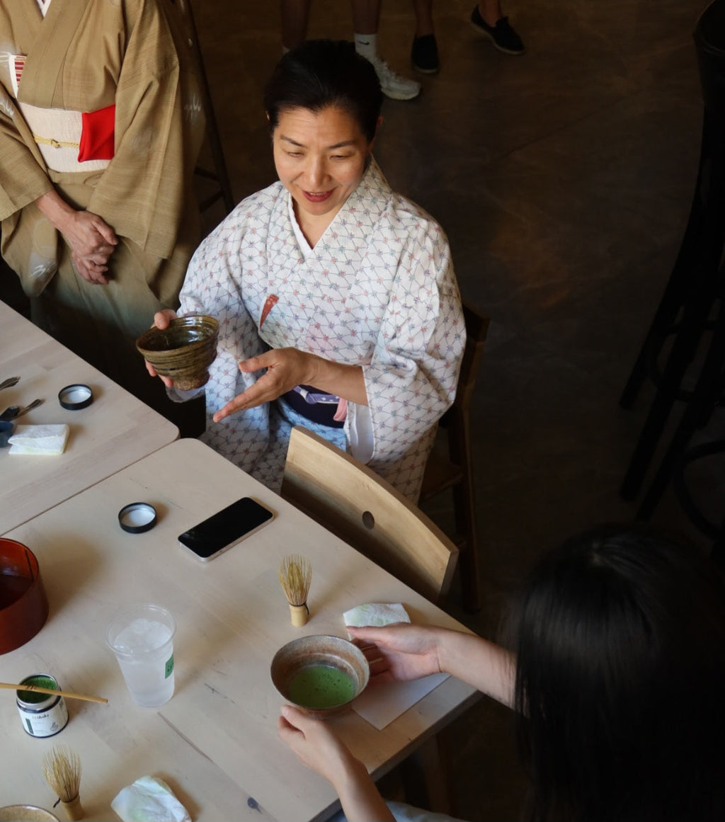 Traditional tea ceremony with participants in formal attire around a table.
