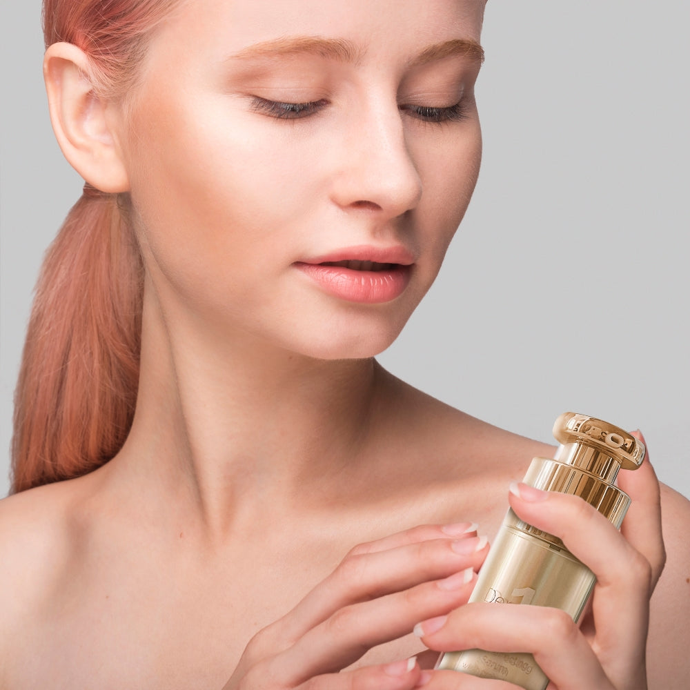 Young woman holding a gold pump bottle of Derm #1 Skincare Skin Perfecting Serum, highlighting a facial serum for rosacea-prone, acne-prone, and sensitive skin with a clean beauty skincare aesthetic.