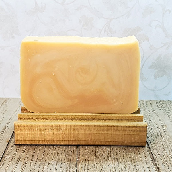 Bar of soap on a wooden stand with a light background. Fresh oranges with a background of soft vanilla and ripe raspberries&nbsp;make up the scent of this lovely orange blossom soap.
