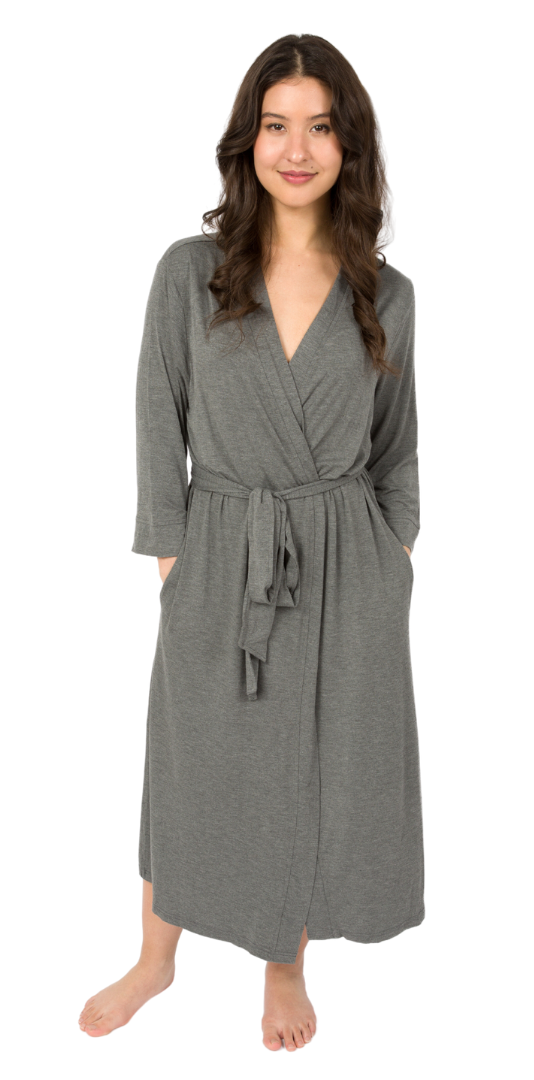 Woman wearing a soft gray wrap maternity robe with three-quarter sleeves, a self-tie waist, and side pockets, standing barefoot on a white background.