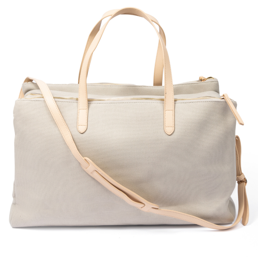 Beige canvas hospital tote bag with dual top handles, an adjustable shoulder strap, gold-tone zipper closure, and multiple storage compartments on a white background.