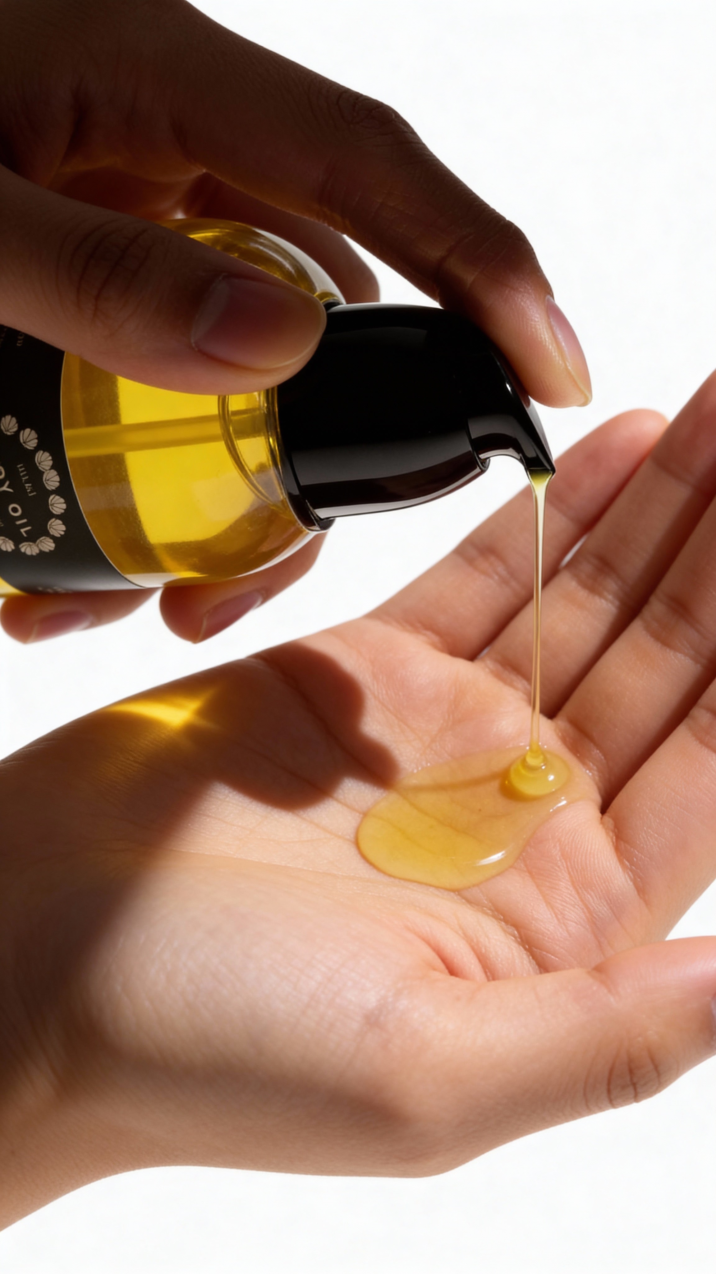 Hand pouring yellow liquid from a bottle into another hand on a white background. The Lymphatic Detox System