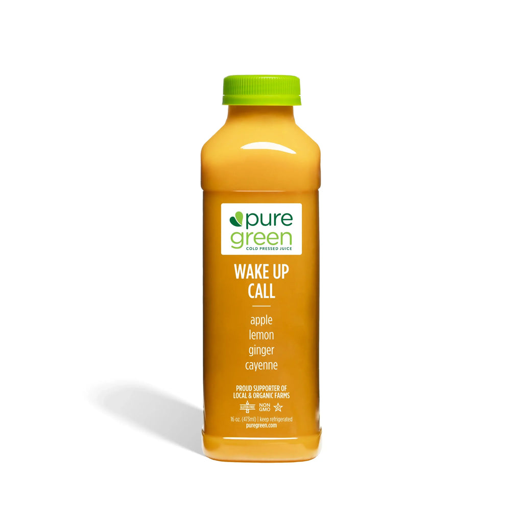 Orange juice bottle labeled 'pure green Wake Up Call' on a white background. Cold-Pressed NON-GMO Juice Drink with Apple, Lemon, Ginger and Cayenne, No Added Sugar, Gluten-Free