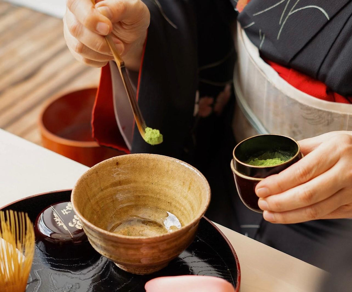 Person preparing a traditional dish with a wooden spoon and ceramic bowl.