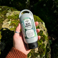 Hand holding Wonderfully Made Bug Repel Lotion with natural essential oils, organic ingredients, no parabens and natural preservative outdoors in a wooded setting