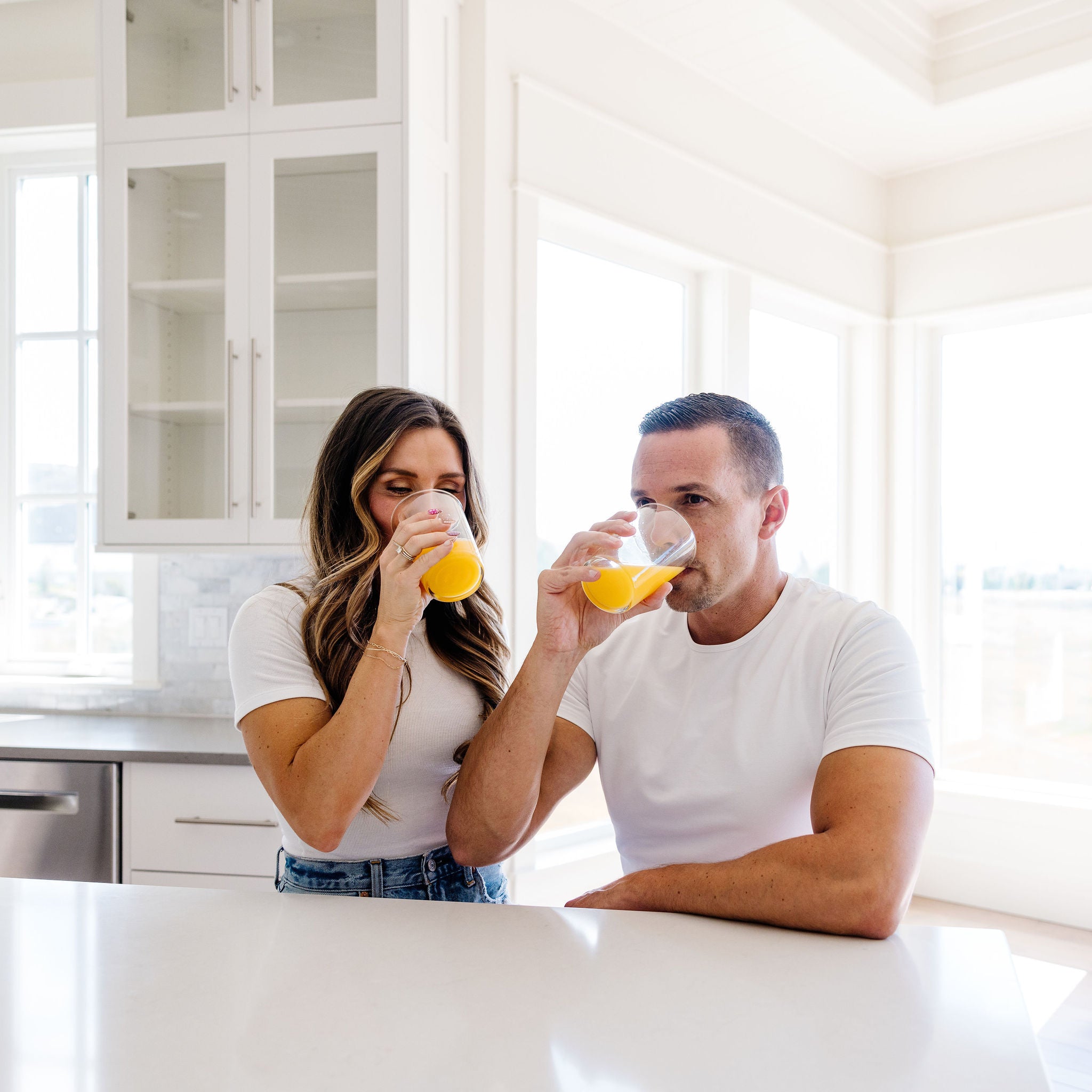 Man and woman drinking orange juice in a kitchen
