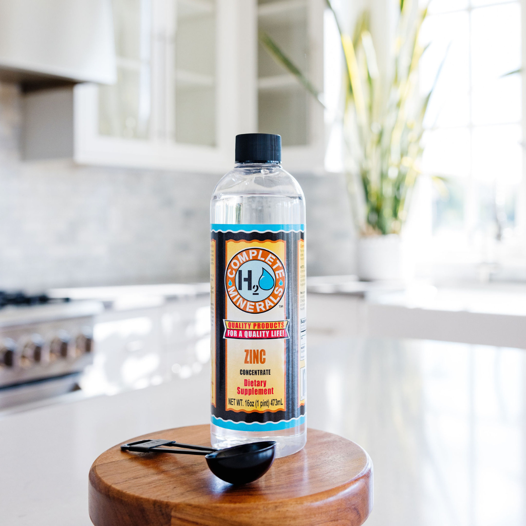 Bottle of H2O Complete Minerals Zinc supplement on a wooden stand in a kitchen.