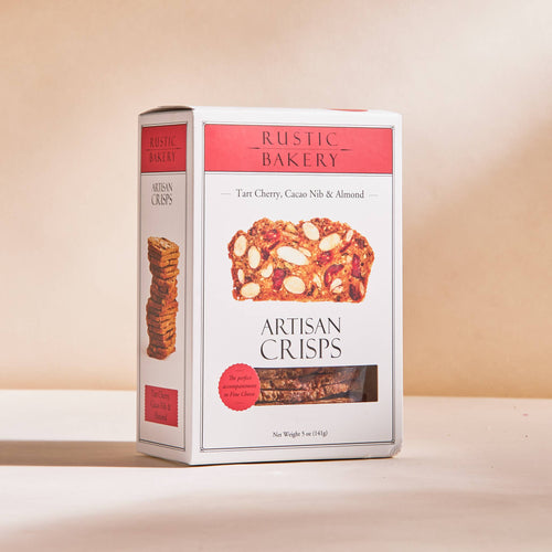 Rustic Bakery Tart Cherry, Cacao Nib & Almond Artisan Crisps box packaging displayed on a light beige background.
