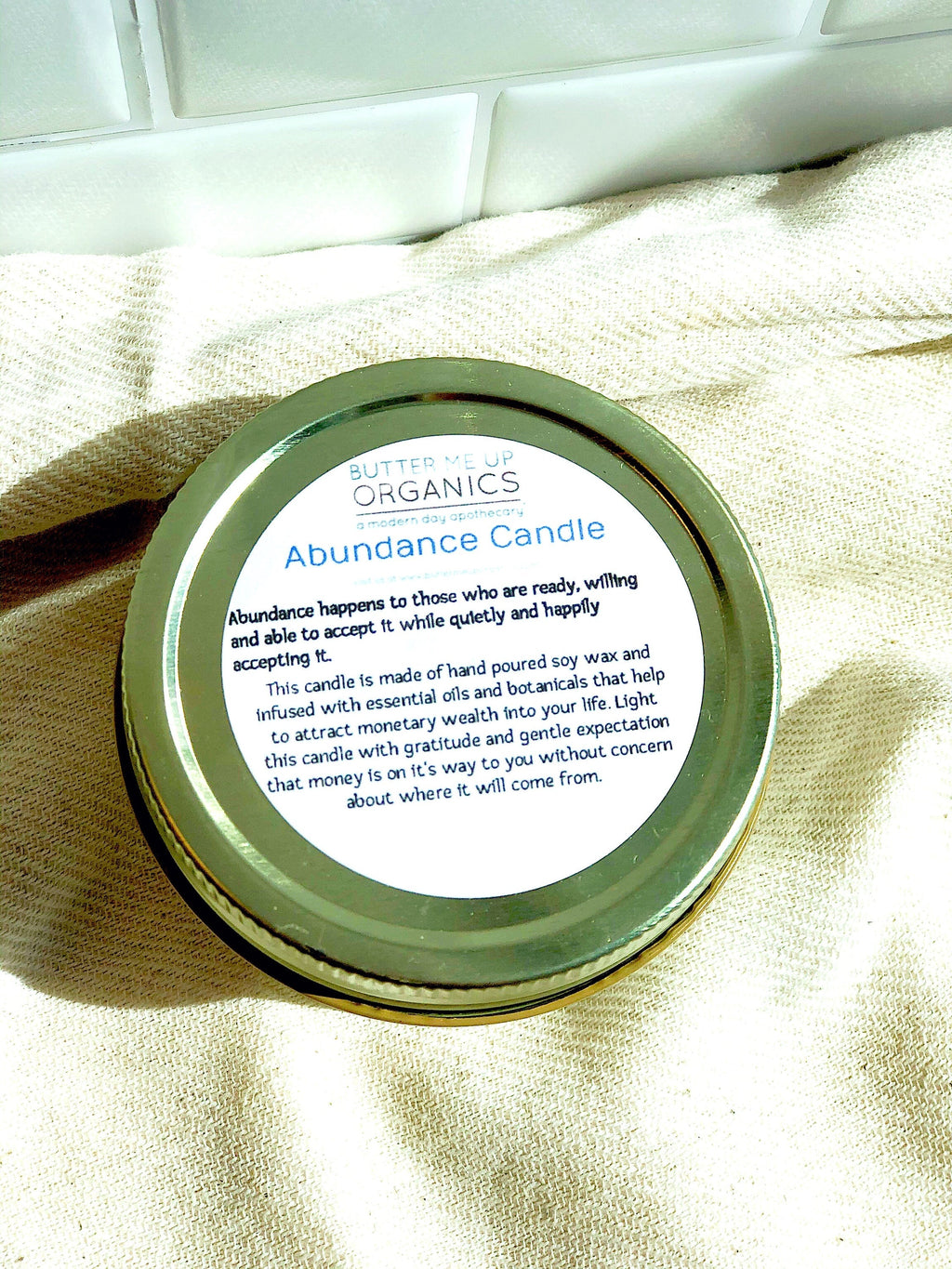 Abundance candle with label on a beige fabric background