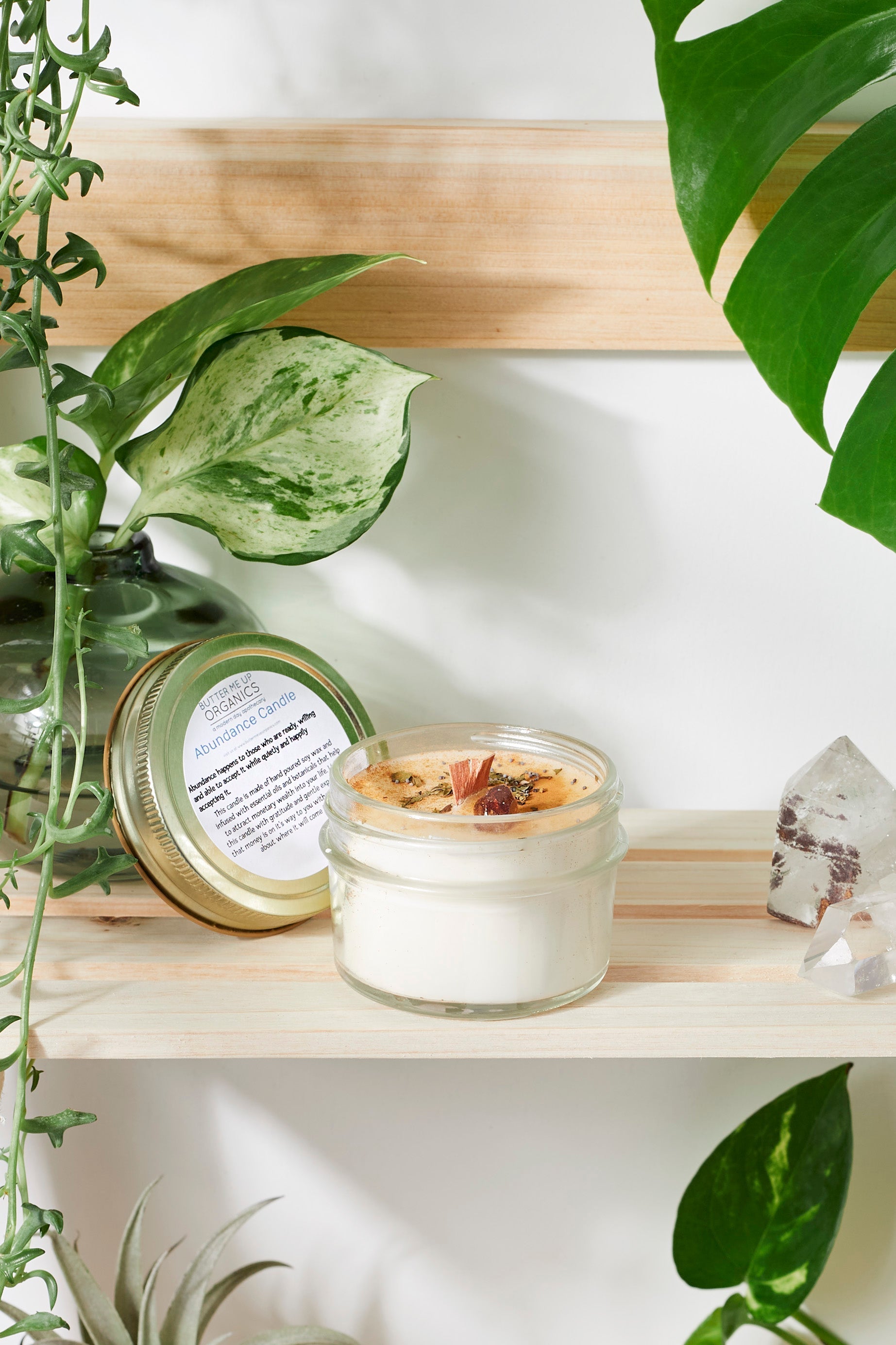 Jar of candle with decorative elements on a shelf with plants