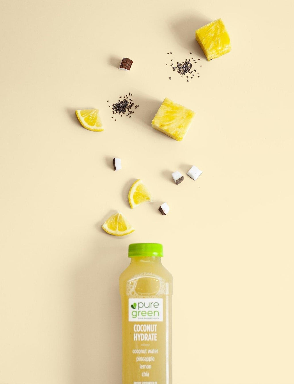 Pure Green coconut water bottle with lemon slices and cubes on a beige background. PURE GREEN COCONUT HYDRATE  Cold-Pressed NON-GMO Juice Drink with Coconut Water, Pineapple, Lemon and Chia, No Added Sugar, Gluten-Free