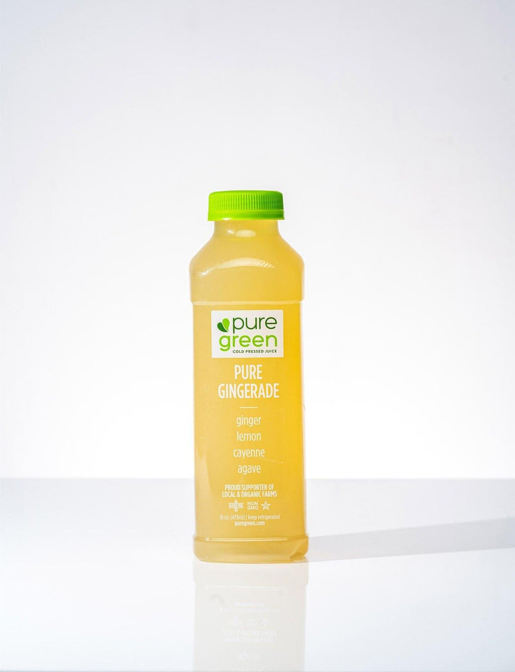 Bottle of pure green pure gingerade on a white background. PURE GREEN PURE GINGERADE Cold-Pressed NON-GMO Juice Drink with Filtered Water, Ginger, Lemon, Agave, and Cayenne, No Added Sugar, Gluten-Free