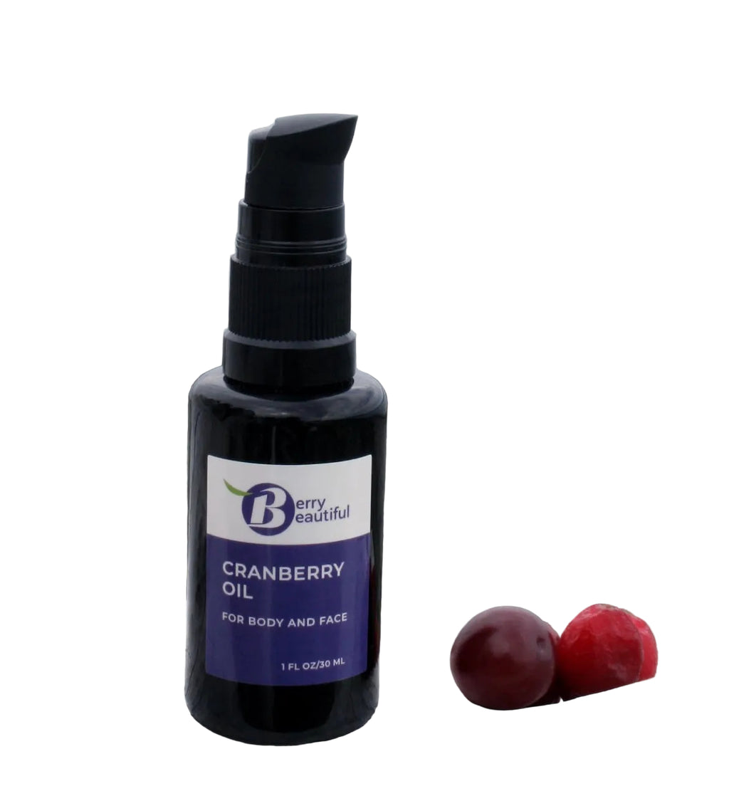 Bottle of Berry Beautiful cranberry oil on a wooden surface with berries.