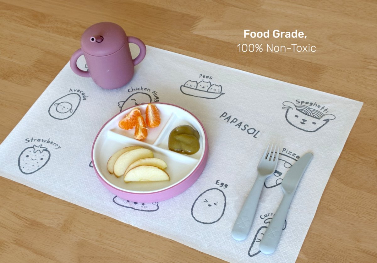 Children's placemat with cartoon illustrations, divided plate, fork, and knife on a wooden table. Baby placemats.