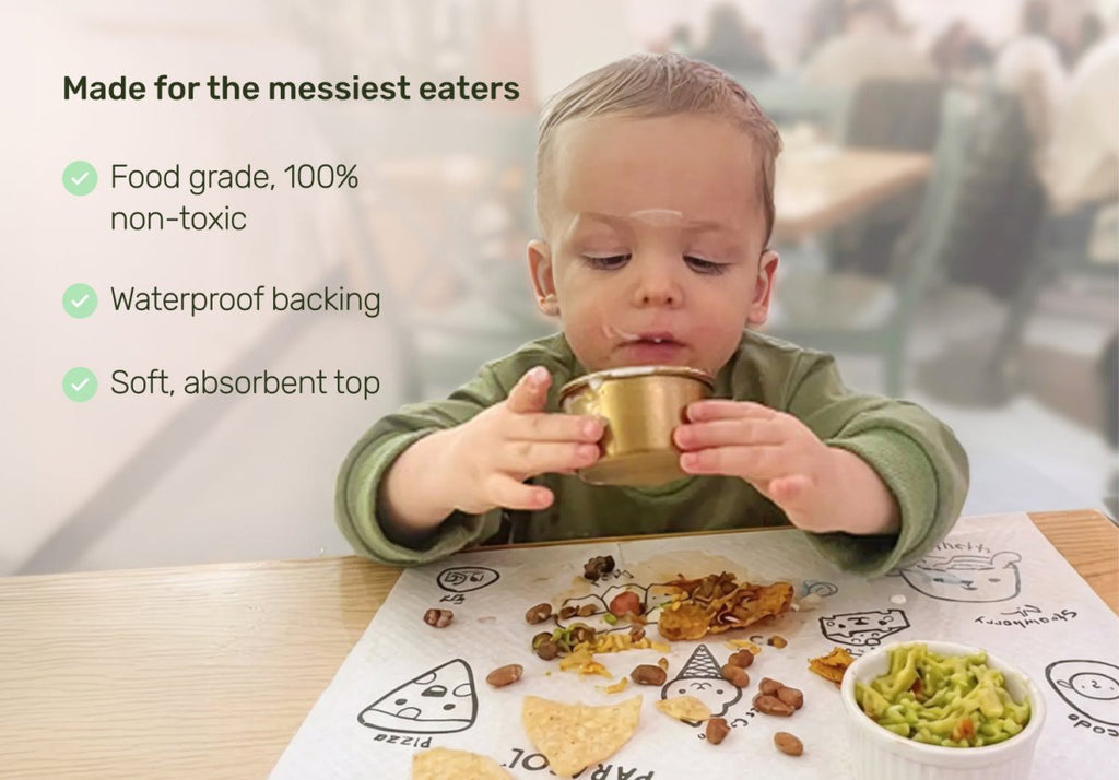 Child eating at a table with a mat, surrounded by food, with text about product features. Baby placemats.