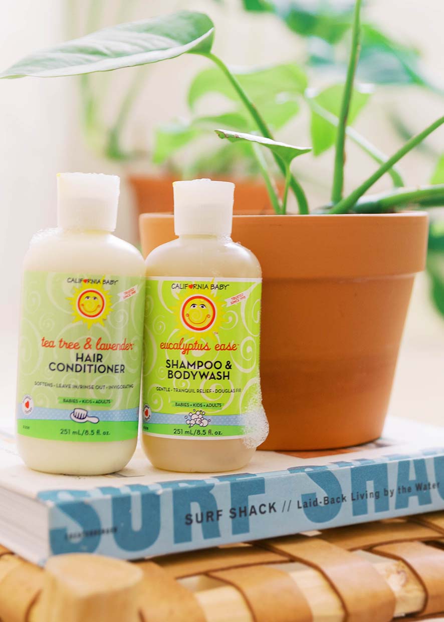 Two bottles of California Baby products on a surfboard with plants in the background California Baby® Eucalyptus Ease™ Shampoo & Bodywash made from Pure Essential Oils, USDA Certified Biobased Product 100% Plant Based