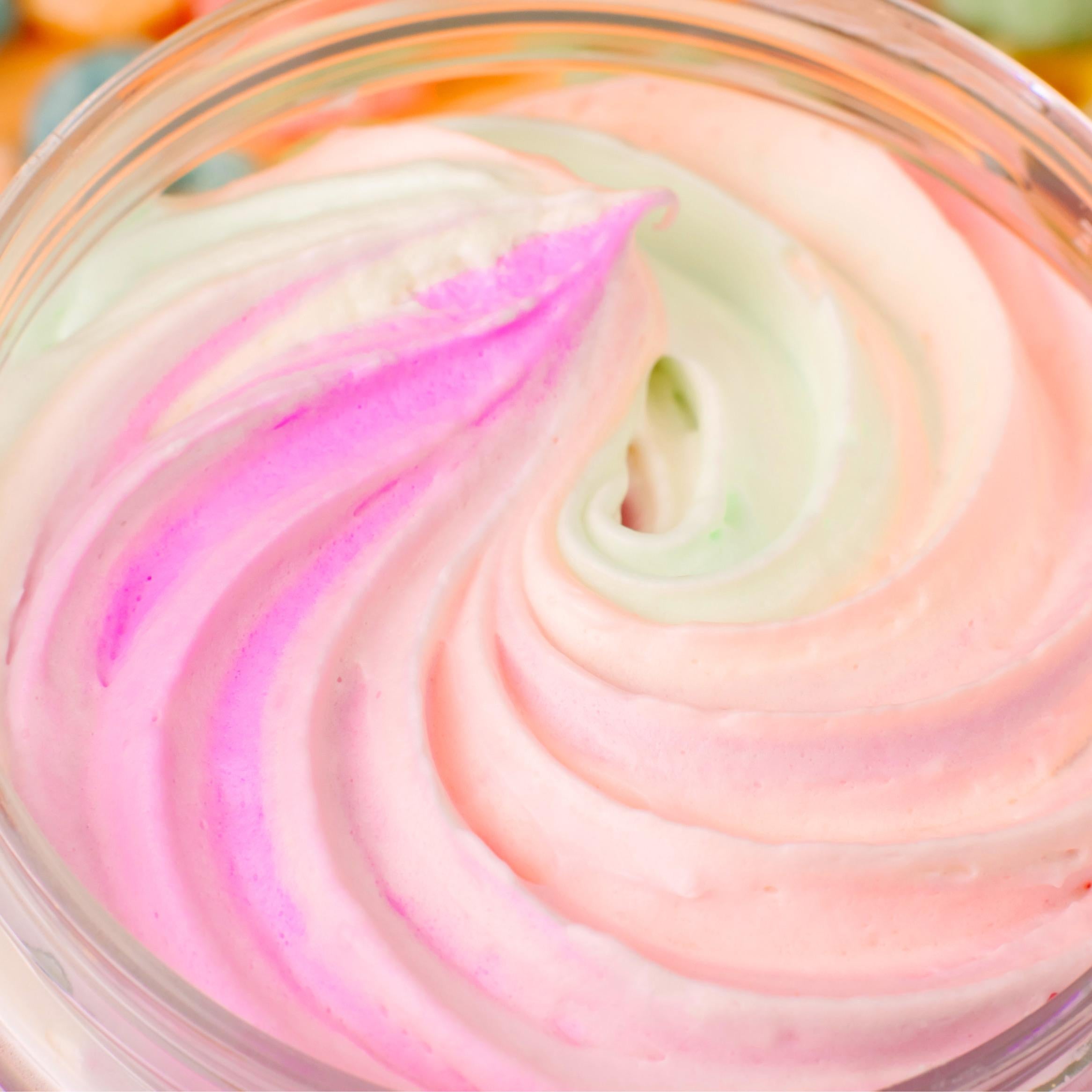 Top-down close-up of AMINNAH FRUITY PEBBLEZ Whipped Body Butter featuring a fluffy pastel swirl of pink, white, peach, and light green whipped body butter inside an open jar. Rich moisturizing formula made with shea butter, mango butter, vitamin E, and essential oils to help nourish, soften, and hydrate skin. Clean Beauty, cruelty-free, vegan, made with natural ingredients, female-owned brand, made in the USA, available at Tree of Life Grocers.