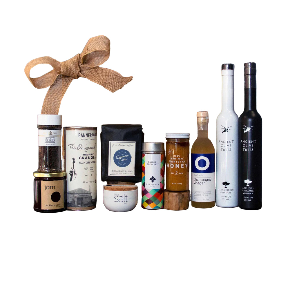 Collection of gourmet food and beverage items on a wooden board with 'The Epicurean Trader' box in the background.