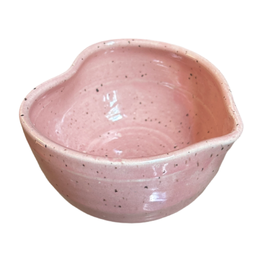 Pink ceramic bowl with speckled texture on a white background