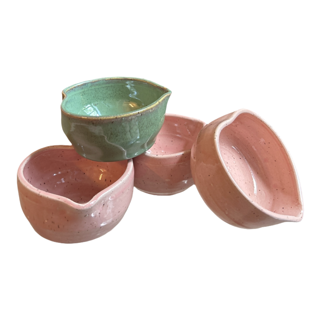 Set of ceramic bowls in green, pink, and peach on a white background