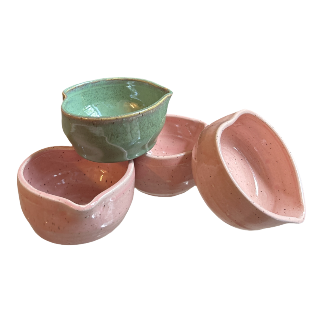 Set of ceramic bowls in green, pink, and peach on a white background