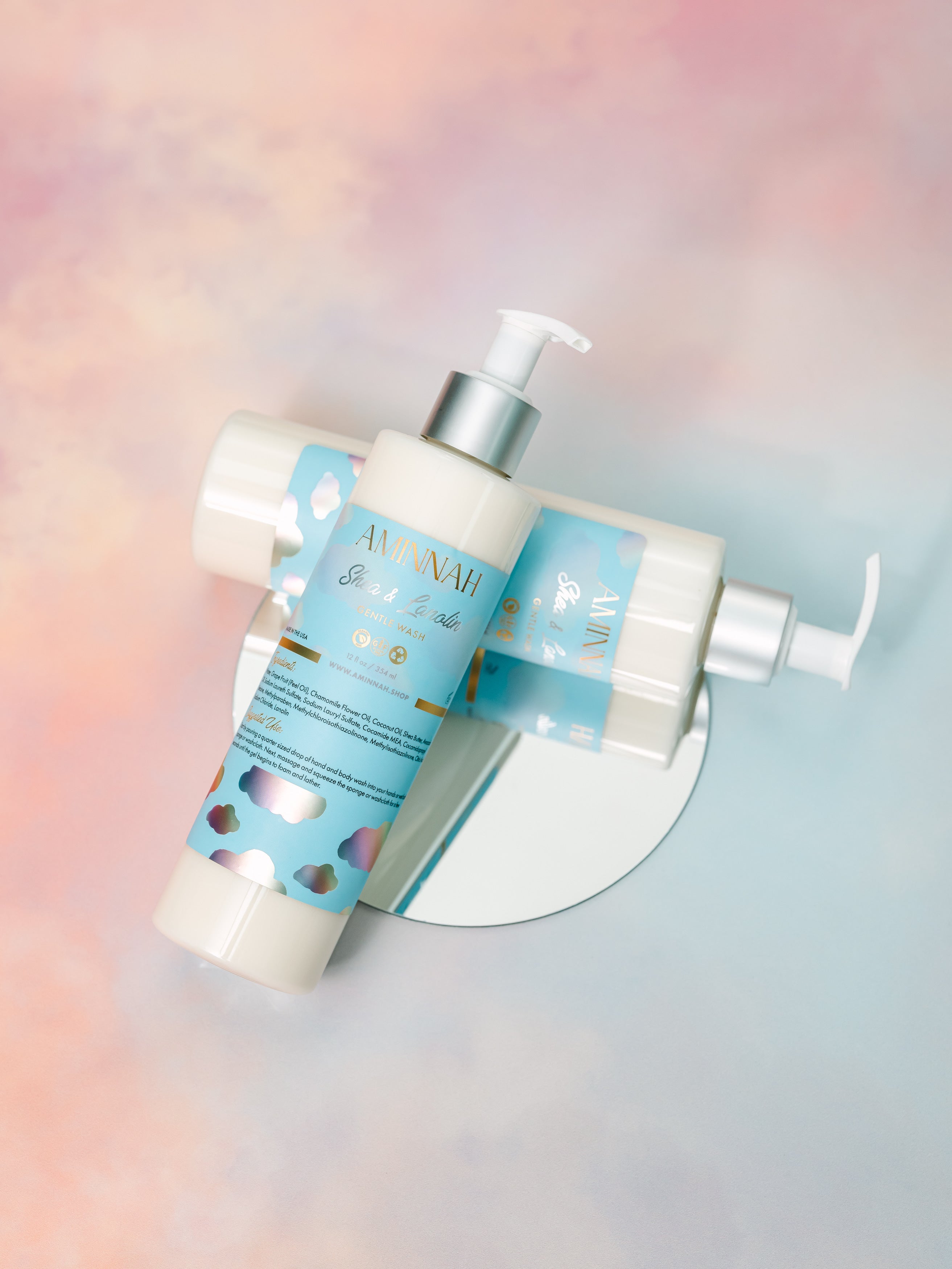 Two skincare products on a round mirror with a colorful gradient background.  Eczema (Shea & Lanolin) Gentle Cleanser. Clean Beauty Commitment, Clean beauty inspired. Made with skin-loving ingredients, Cruelty-free, Female-owned brand