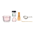 Collection of tea-making tools including a glass cup, container, whisk, and other accessories on a white background.