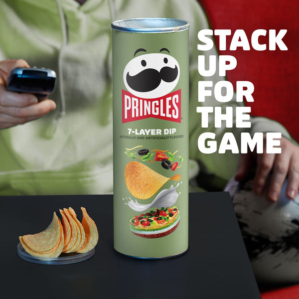 Pringles can with 7-layer dip flavor on a table with people in the background
