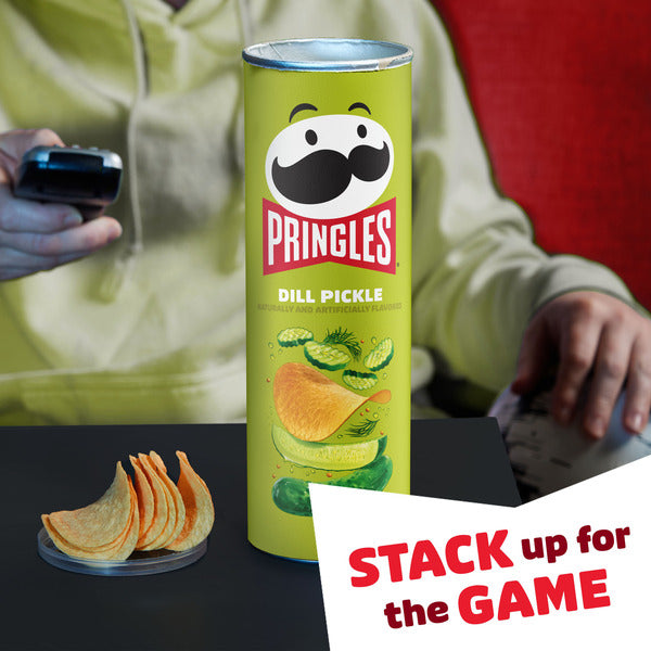 Pringles Dill Pickle can with potato chips and text 'Stack up for the Game' on a blurred background.