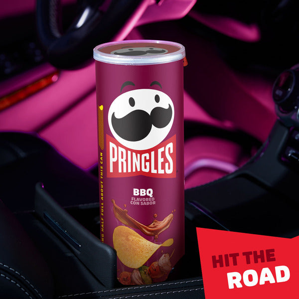 Pringles BBQ flavor can in a car cup holder with 'Hit the Road' text.