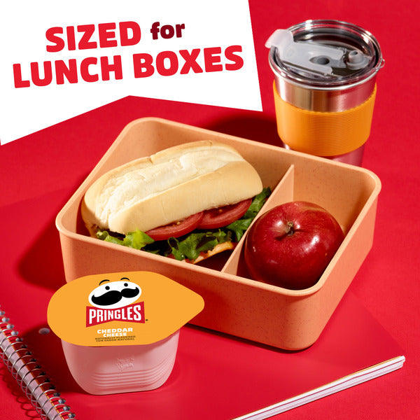 Lunch box with sandwich, apple, and Pringles container on a red background