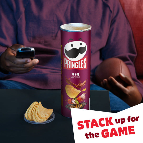 Person sitting on a couch with a Pringles can and chips, holding a phone, with 'Stack up for the Game' text.