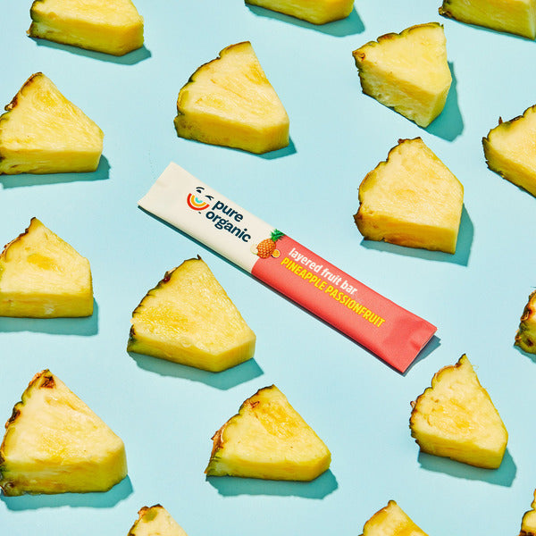 Pure Organic fruit bar with pineapple pieces on a blue background. Pure Organic Pineapple Passionfruit Layered Fruit Bars, Gluten Free, 12 C