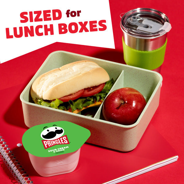 Lunch box with sandwich, apple, and Pringles container on a red background