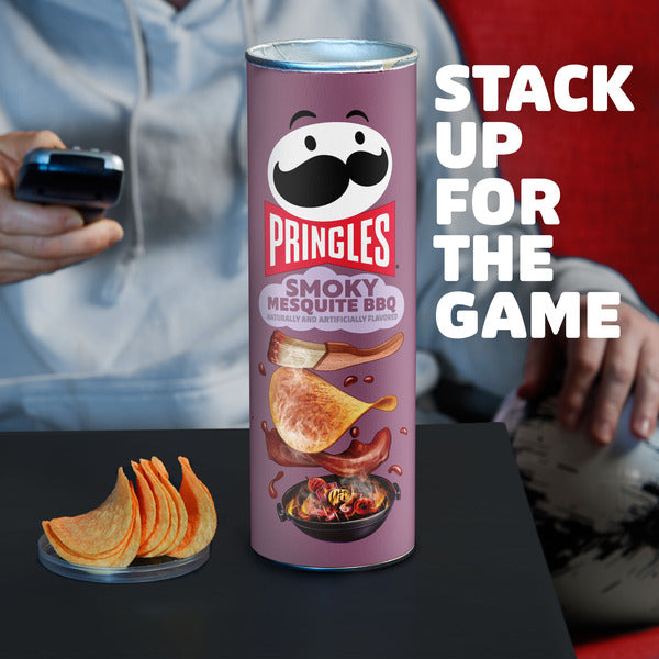 Pringles Smoky Mesquite BBQ can with chips on a table, people in the background
