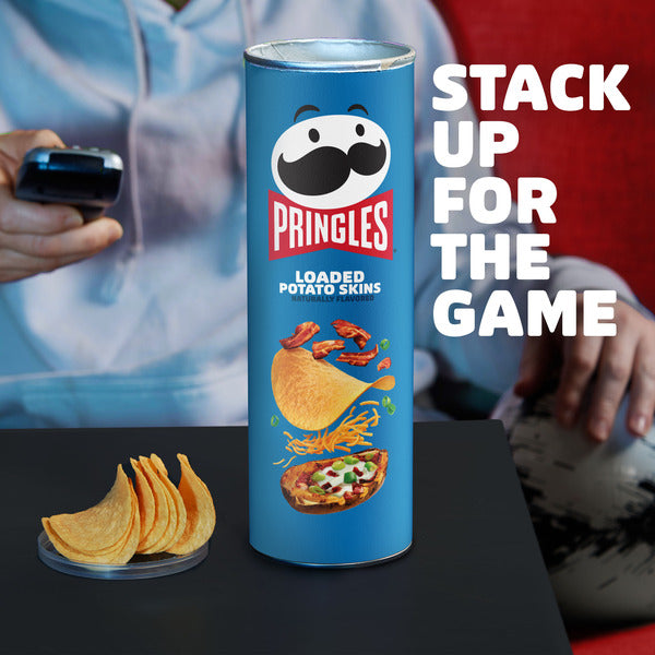Pringles Loaded Potato Skins can with chips on a table, with text 'Stack Up for the Game' in the background.
