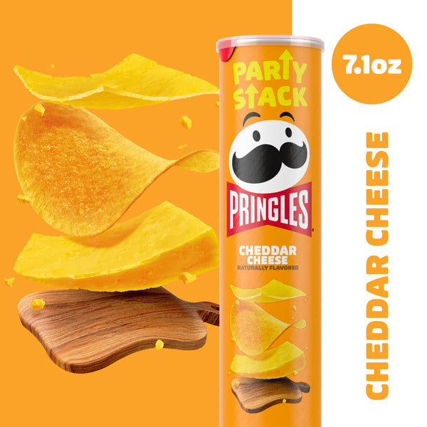 Pringles Cheddar Cheese potato chip can with chips on a cutting board against an orange background