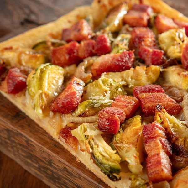 Rectangular pizza with bacon and brussels sprouts on a wooden board