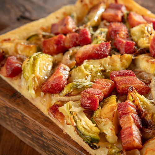 Rectangular pizza with bacon and brussels sprouts on a wooden board