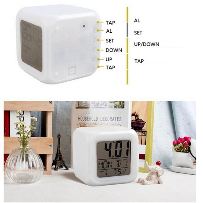 White digital cube clock with buttons and display on a white surface.