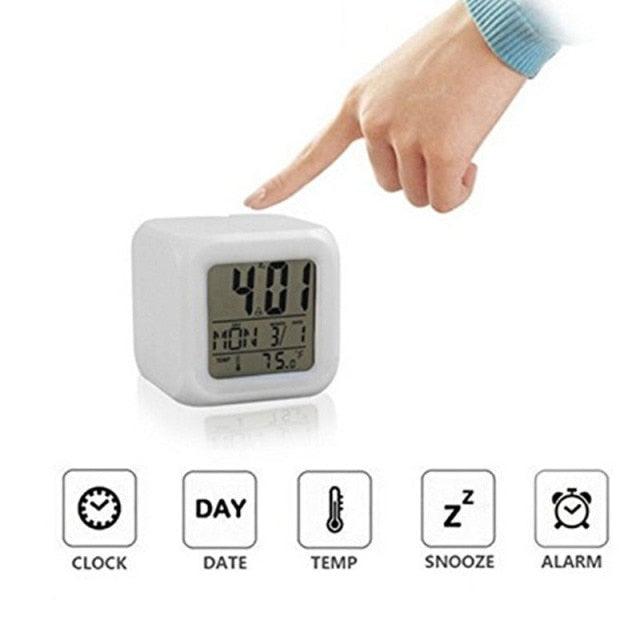 Digital clock with a hand pointing at it, displaying time and date on a white background.