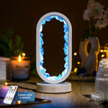 Decorative lamp with blue LED lights on a table with a candle and remote control. Manifest Success - Clear Quartz Lamp of Achievement