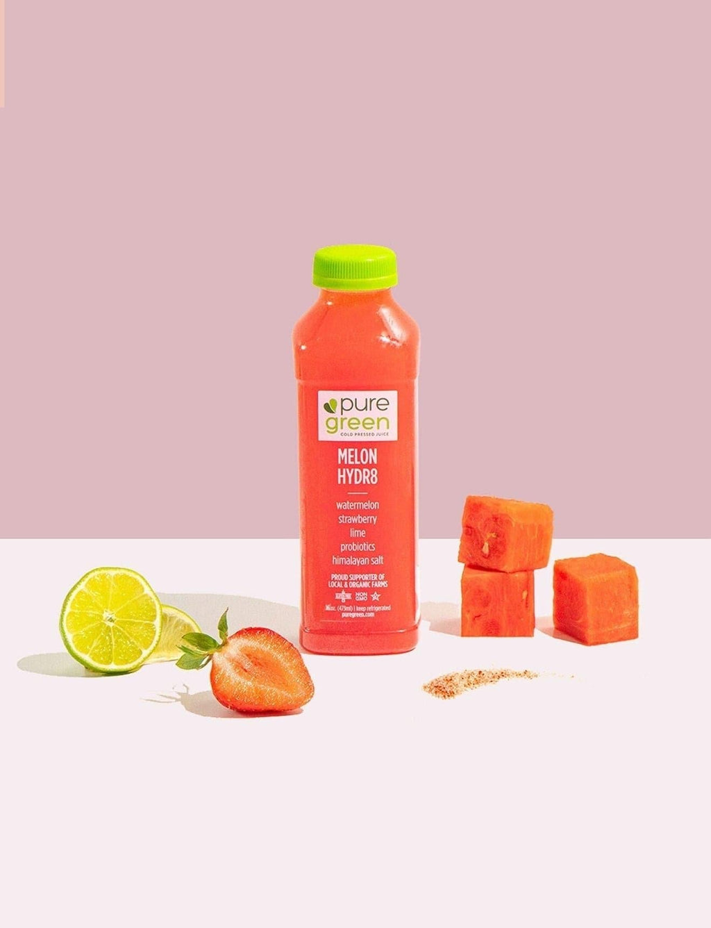 Bottle of pure green juice with melon hydr8 flavor on a white surface with fruit and seeds. Watermelon, Strawberry, Lime, Probiotics, Himalayan Salt, proud supporters of local and organic farms. The PURE GREEN company cold pressed juice drink.