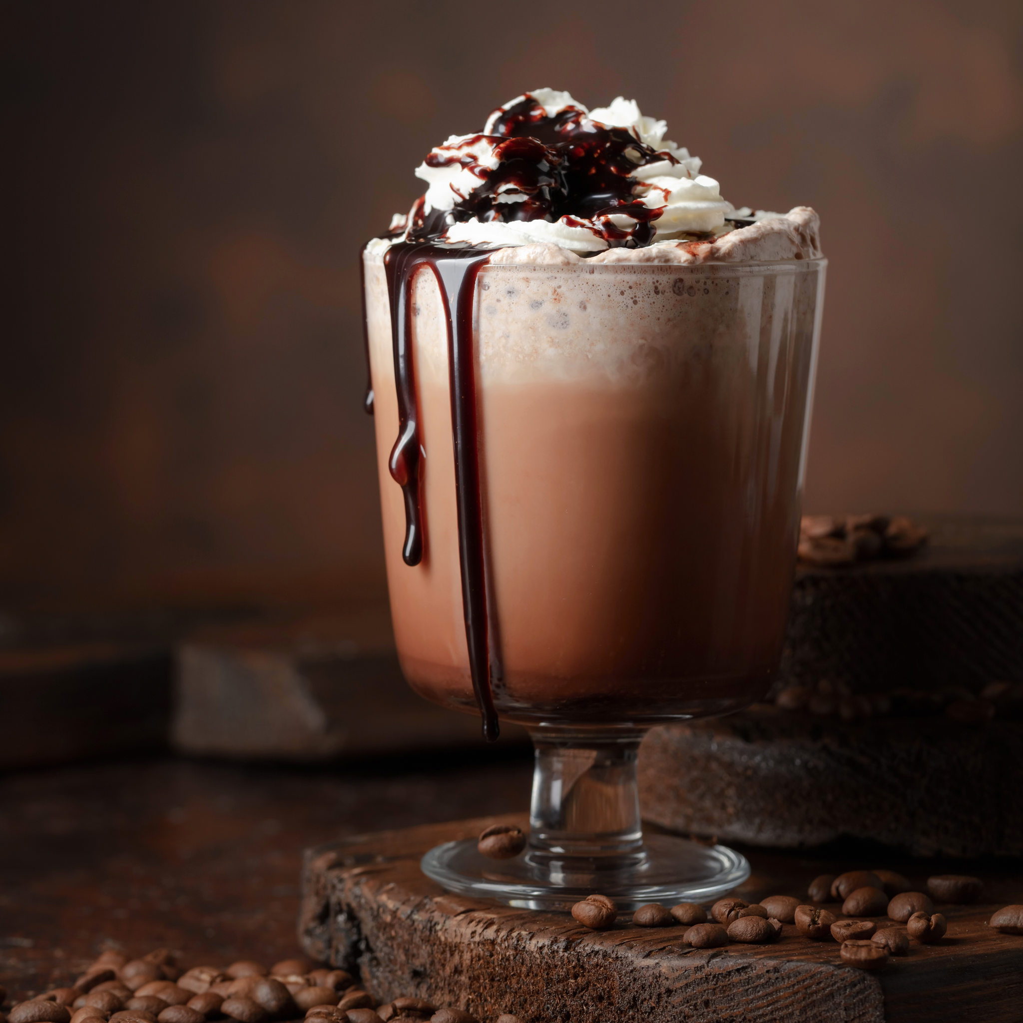 Creamy mocha latte served in a clear glass mug, topped with whipped cream and rich chocolate drizzle, creating a cozy café-style beverage perfect for warming up on chilly days.