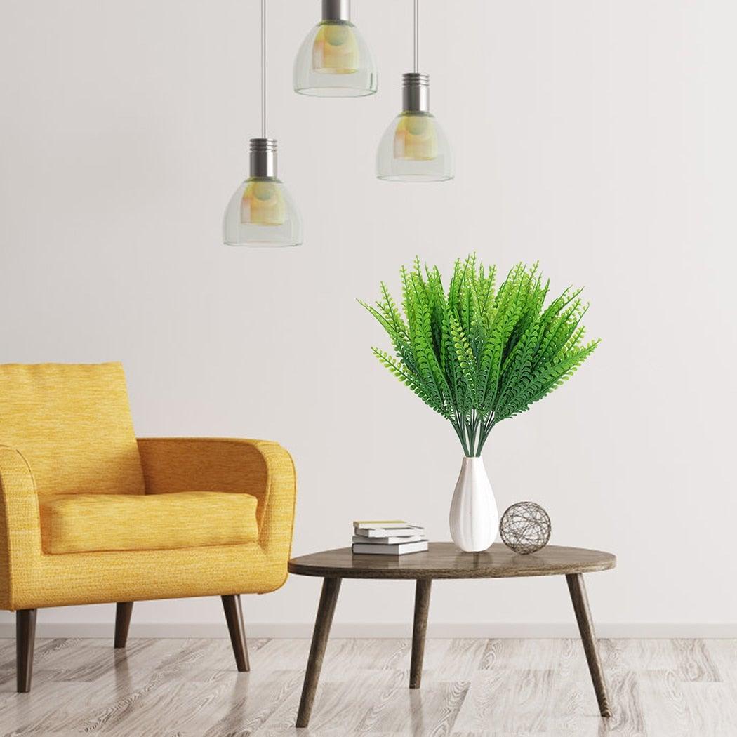 Yellow armchair next to a wooden side table with a plant and decor items against a white wall.