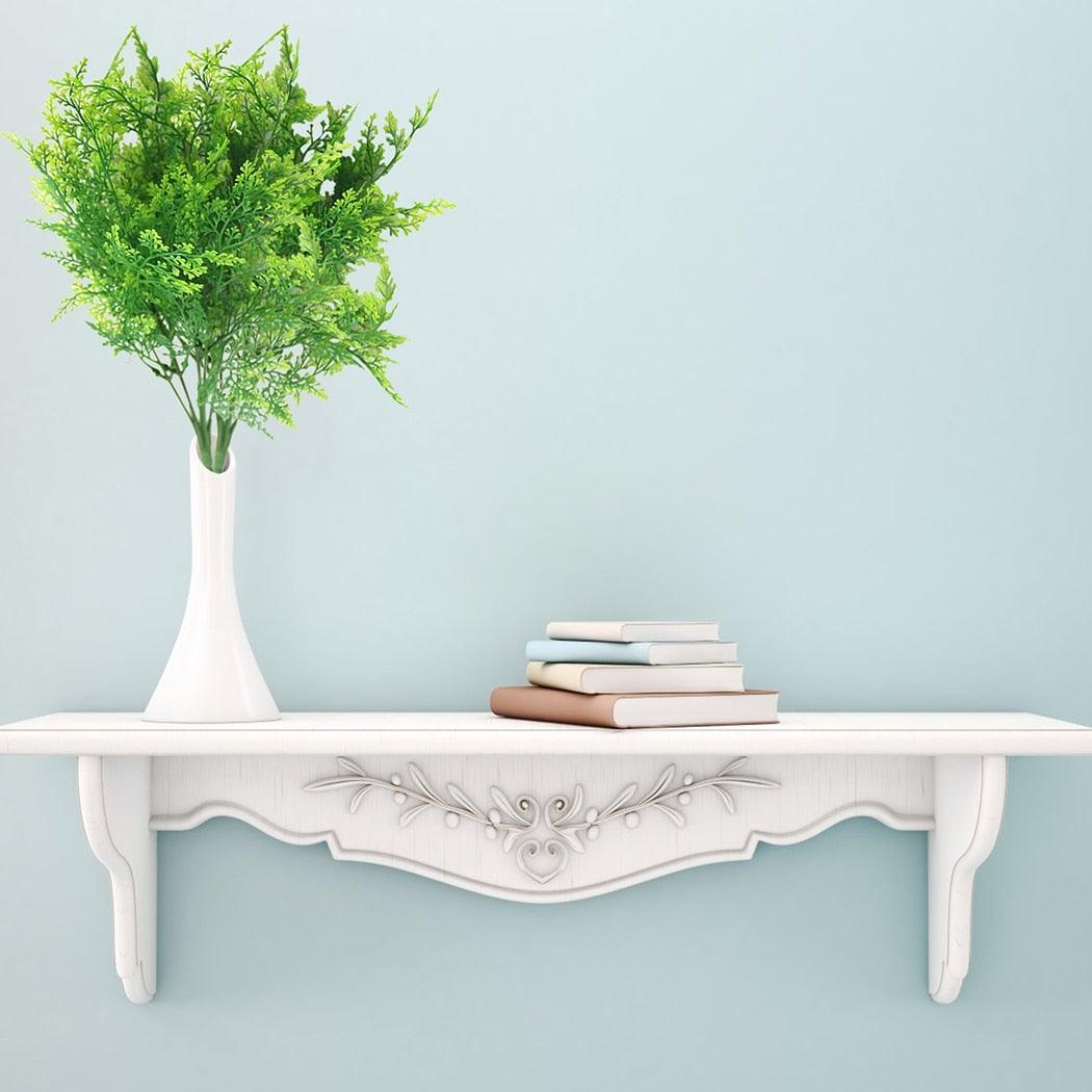 White table with a vase of greenery and books against a light blue wall