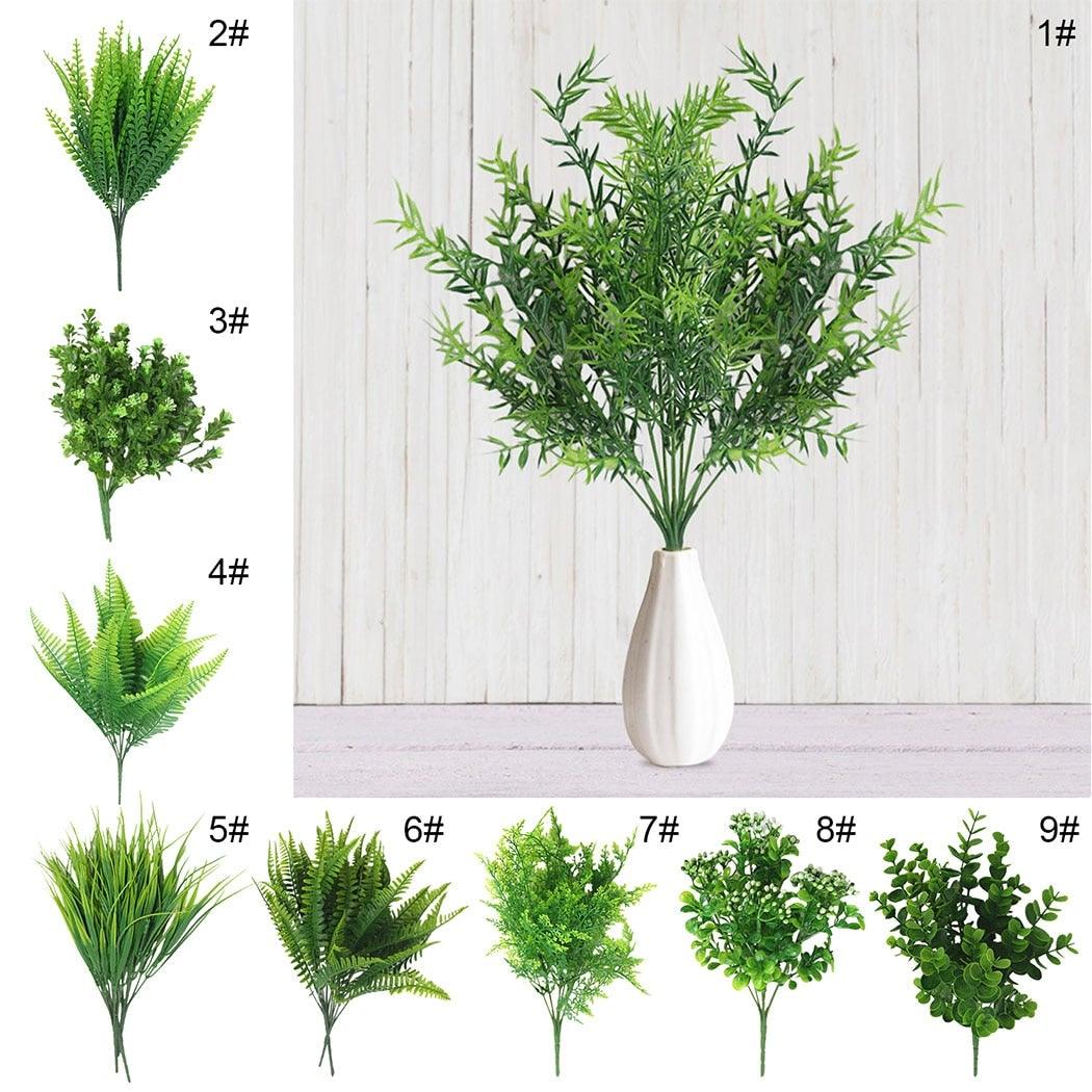 Set of artificial plants with a white vase on a light wooden background