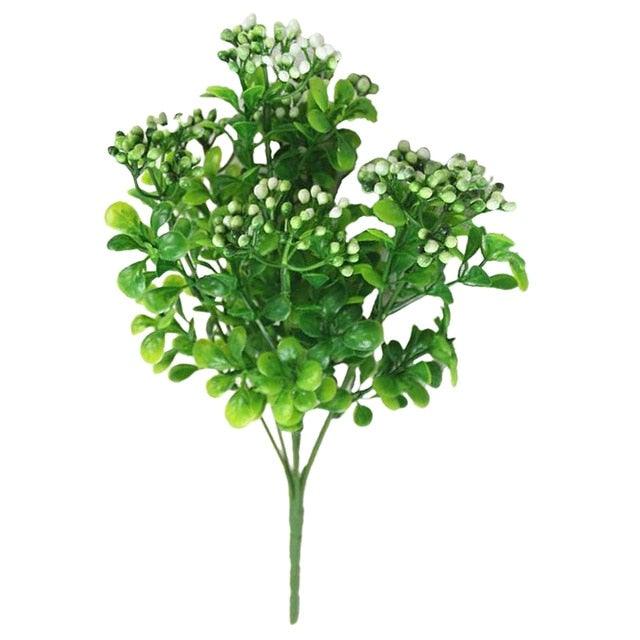 Artificial green plant with small white flowers on a white background