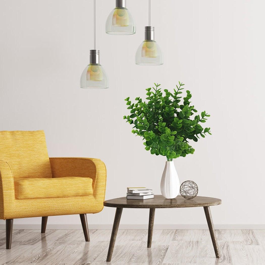 Yellow armchair next to a wooden side table with a green plant in a white vase.